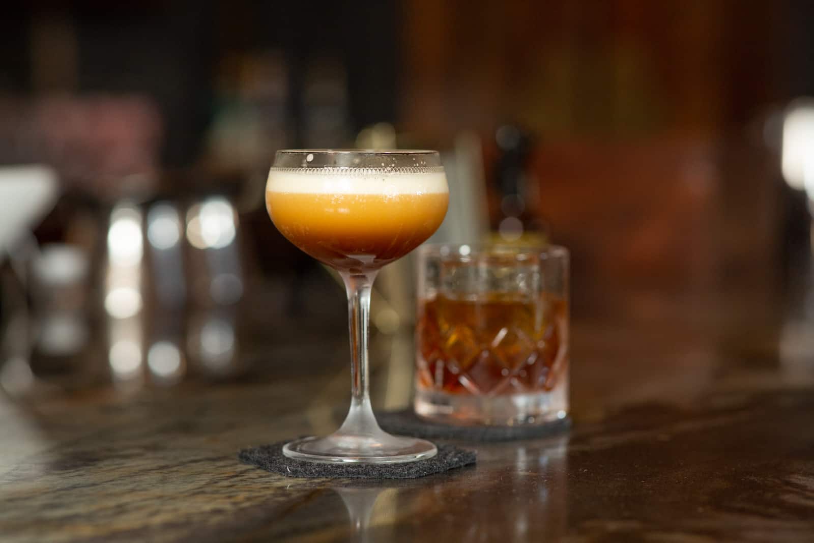 two cocktails sitting on bar